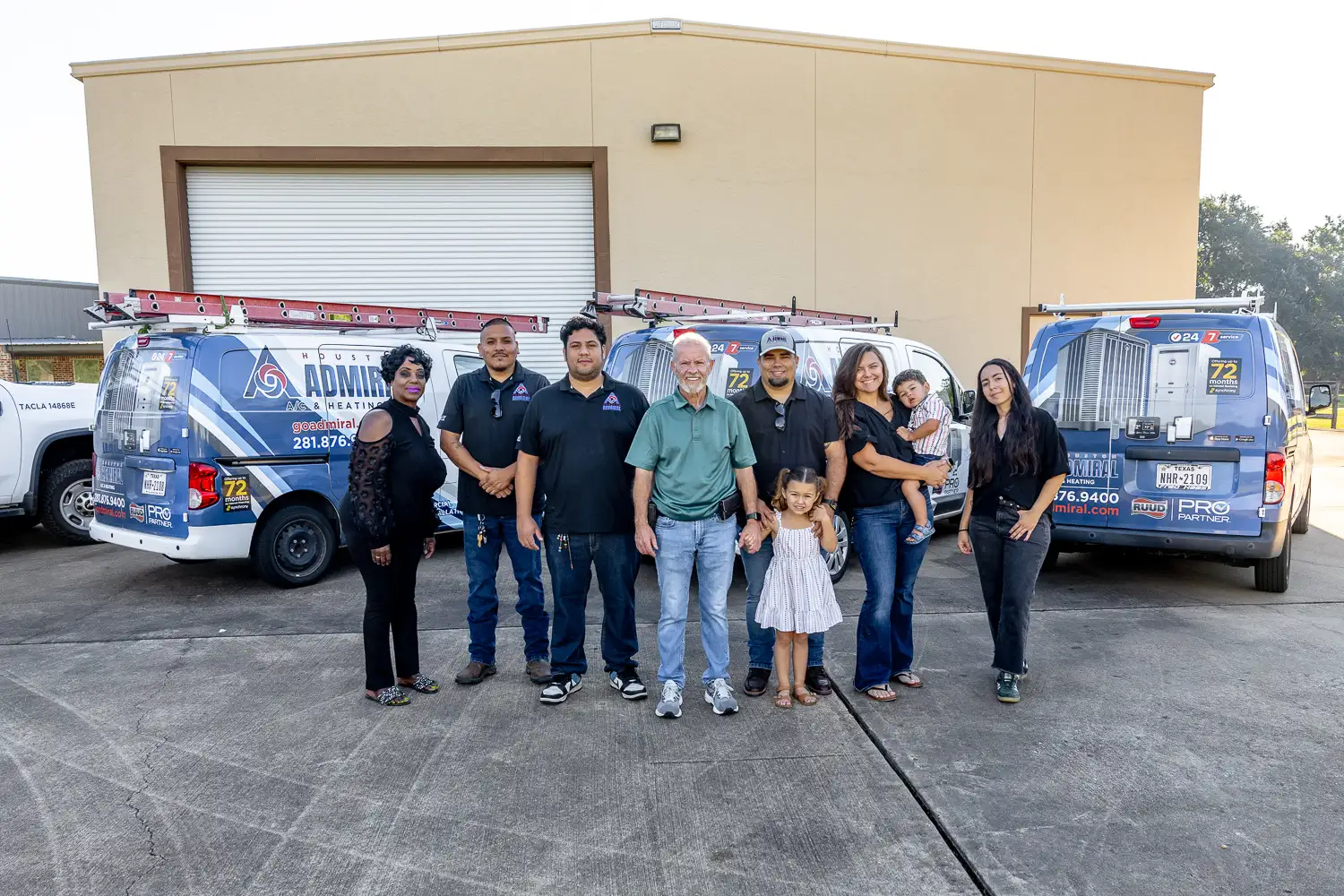 Houston Admiral team standing in front of branded service vans outside the company building.